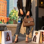 Stylish individual showcasing a luxurious 레플리카 handbag in a vibrant urban setting.